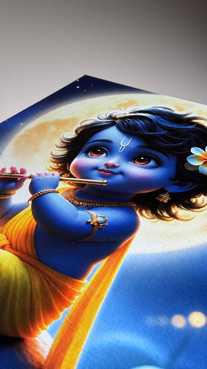 A close-up of a printed artwork or poster showing a blue-skinned child playing a flute, with a yellow drape, dark hair, and a flower, set against a blue and cream background.